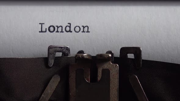 Typing city name London on a vintage typewriter. Close up.