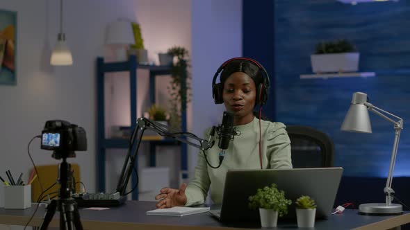 African Social Media Woman Looking in Laptop Talking at Microphone