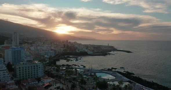 Aerial Panorama of Puerto De La Cruz Resorts and Pools Surrounded By Sea Waves on Sunset Tenerife