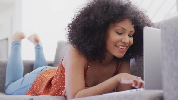 Woman using laptop while laying on the couch at home