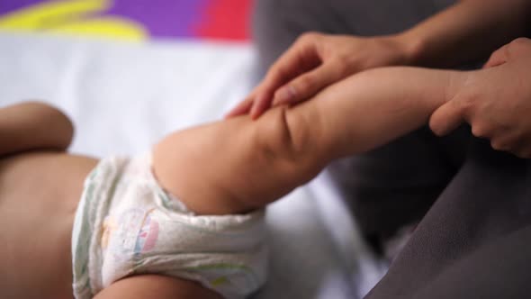 Female Hands Massage the Leg of a Lying Infant