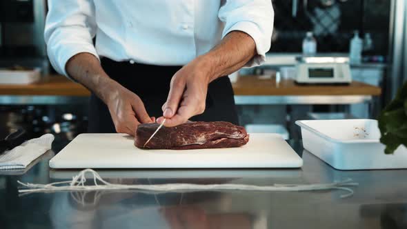 Close-up: The chef cuts the meat of the filet mignon with a knife. The process of preparing food