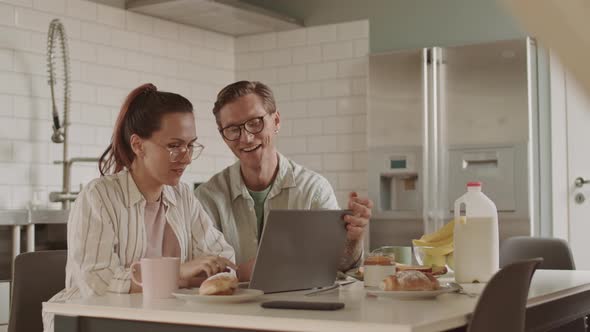 Spouses Using Laptop at Kitchen Table