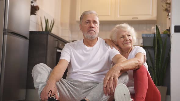 Portrait of a Happy Mature Couple Sitting on the Floor and Resting After Morning Gymnastics Yoga