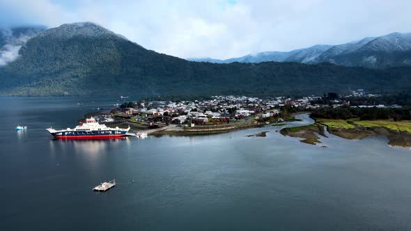 Aerial view truck left of Hornopiren, Chile. Ferry in the small harbor and snow-capped mountains on