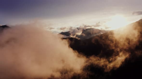 The Drone Flies Through the Clouds at the Mountain Peaks