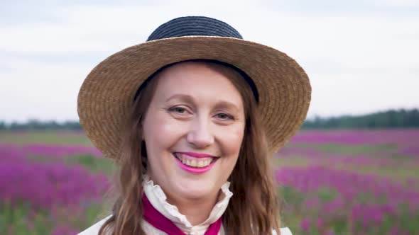 Girl in a Blue Dress with a White Blouse and a Straw Hat Walks Along