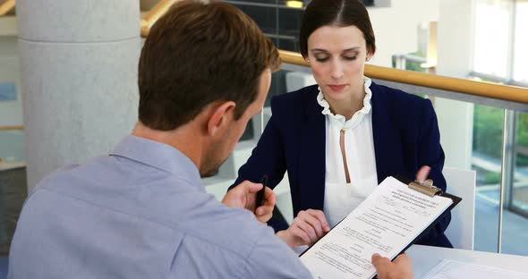 Executive taking sign of colleague on document 