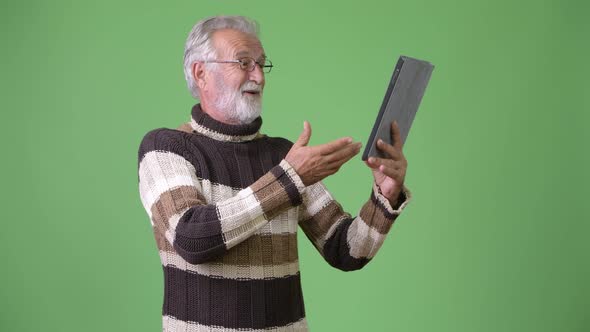 Handsome Senior Bearded Man Wearing Warm Clothing Against Green Background