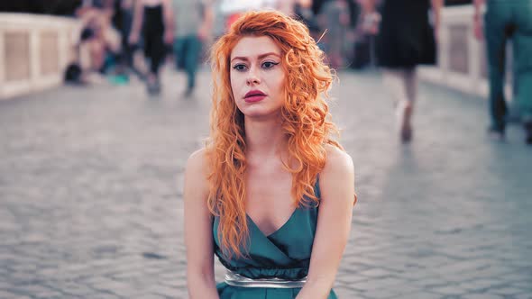 beautiful red-haired woman sitting on the bridge in Trastevere with worried look