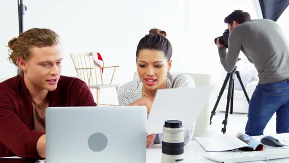 Photographer and female model discussing over laptop