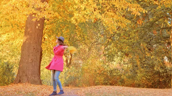 Happy Woman with Autumn Leaves Walking in Park