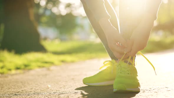 Woman Tying Shoelaces While Jogging or Walking at Sunset