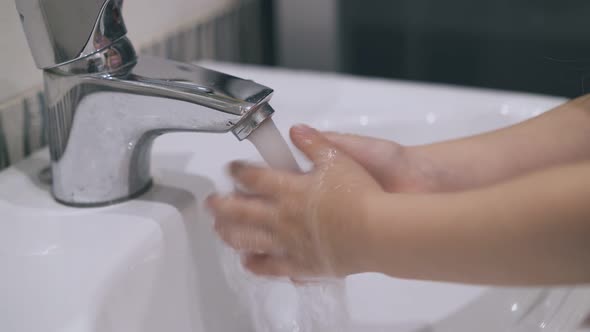 Little Girl Washes Hands with Water Over Sink Close View