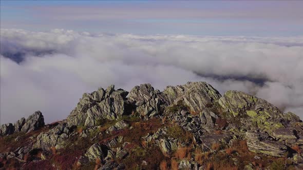 Mountain Top Rocky Summit Surrounded with Clouds and Fog. Aerial View of Severe Conditions on High