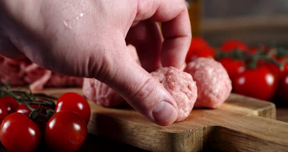 The Man's Hand Put Raw Meatballs on a Cutting Board