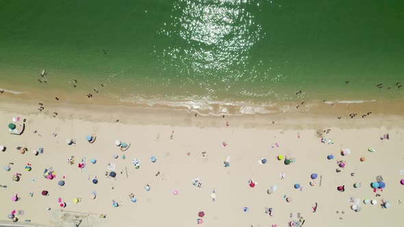 Aerial top down view along beautiful Sandy beach, Green water and Colorful umbrellas