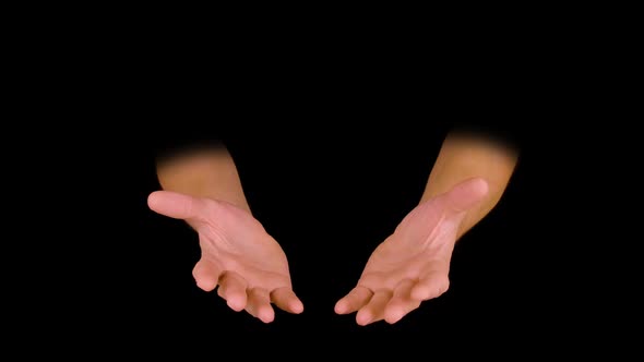 Male Hands Holding Something Between Palms Isolated on Black Background