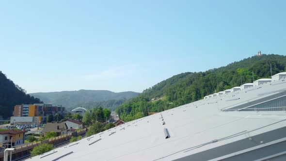 Big sports hall covered with white insulation panels and light plastic domes on top of it. Aerial 4k