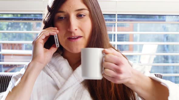 Woman having coffee while talking on mobile phone