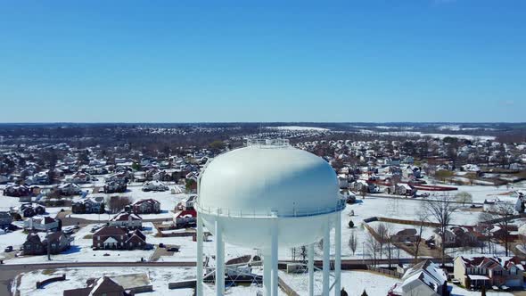 Vertigo shot of a water tower with a snow filled neighborhood in the background