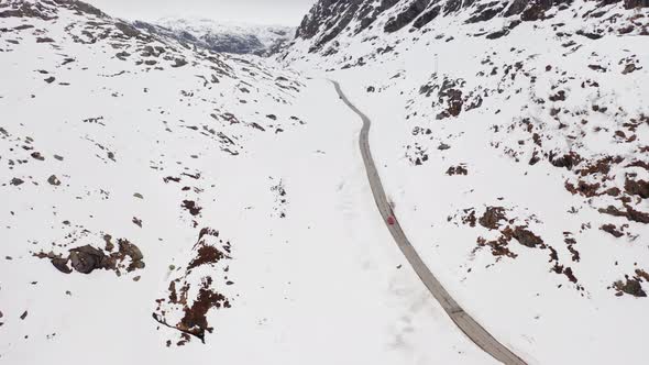 Dramatic landscape at mountain road crossing during harsh winter - unknown car passing in the distan