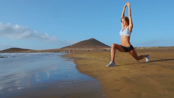 Woman Doing Leg Stretches. Fitness Girl Stretching Legs on Beach Training. SLOW MOTION STEADICAM