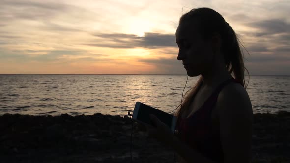 Runner Woman Setting Music on Smartphone at Sunset