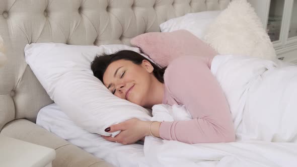 Woman sleeping in comfortable cozy white bed on soft pillow and orthopedic mattress