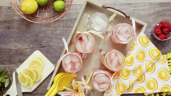 Step by step. Pouring raspberry lemonade with fresh lemons and raspberries in drinking mason jars