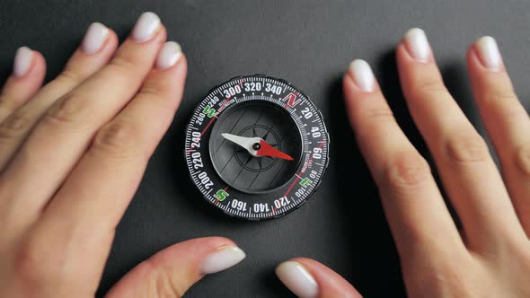 a Modern Compass Lying on a Black Desk with a Red Arrow That Shows the Direction