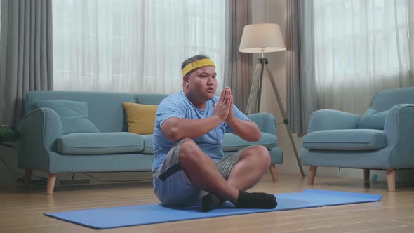 Fat Asian Man Doing Yoga In Sukhasana Pose At Home