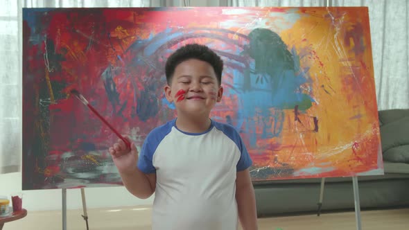 Funny Talented Little Boy Dirty With Paint, Looks At The Camera With A Smile