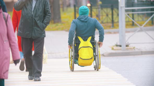 Disabled Man in Wheelchair Crossing the Road at the Daylight