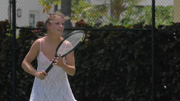 A young woman playing tennis with her boyfriend while on vacation.