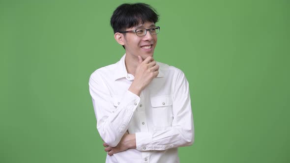 Young Happy Asian Businessman Smiling While Thinking