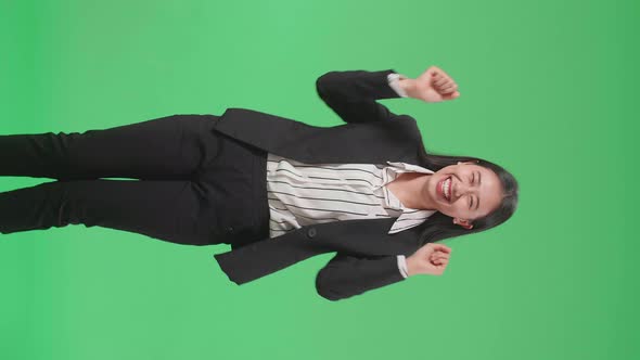 A Smiling Asian Business Woman Dancing While Standing On Green Screen Background In The Studio