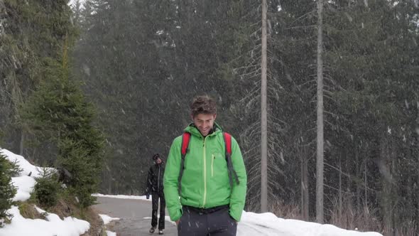 A man and woman couple hiking while it is snowing in mountains in the winter