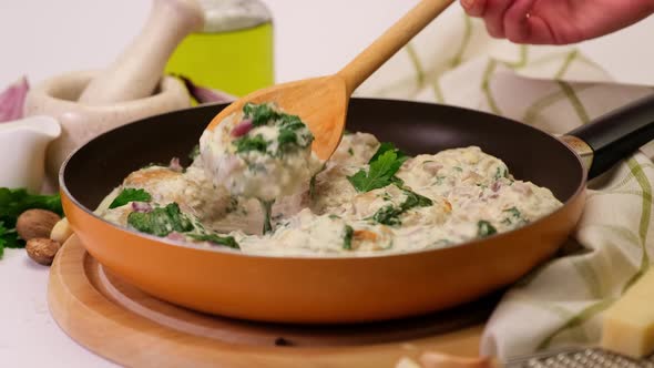 Delicious Small Meatballs with Spinach in a Creamy Sauce in the Frying Pan