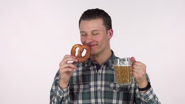 Cheerful Young Man Holding Mug of Beer, Smelling Delicious Pretzel