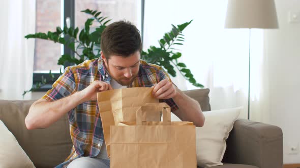 Smiling Man Unpacking Takeaway Food at Home