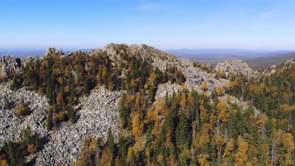 Aerial view of the mountains with rocks and beautiful autumn woods on the slopes