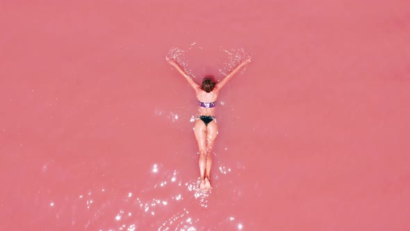 Aerial View. A Beautiful Young Girl Lies on in the Pink Lake, a Bikini, Sunglasses, Pink Clear Water