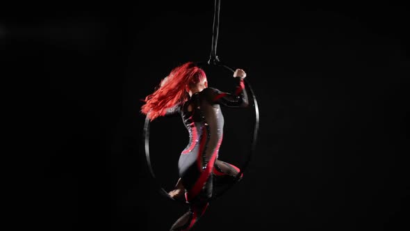 Wide Shot Slim Young Woman in Black and Red Costume Sitting on Air Hoop Spinning in Slow Motion