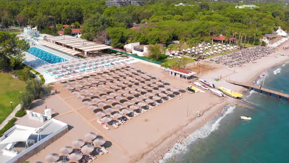 Flight Over the Beach with Umbrellas Towards the Pool in a Luxury Hotel