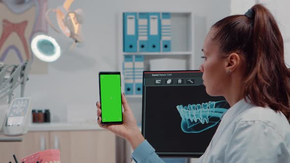 Close Up of Orthodontist Holding Smartphone with Green Screen