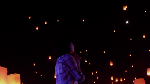 Asian woman watches as sky lanterns fly Into the night sky