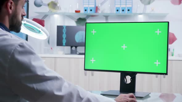 Zoom in Shot of Doctor Working on Computer with Green Screen Mock-up