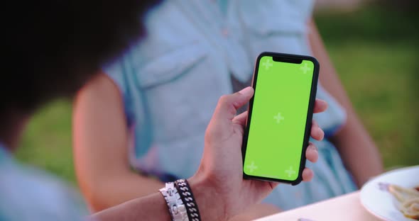 Man Using Green Screen Smartphone Device During Romantic Outdoor Dinner at Sunset .Friends Italian