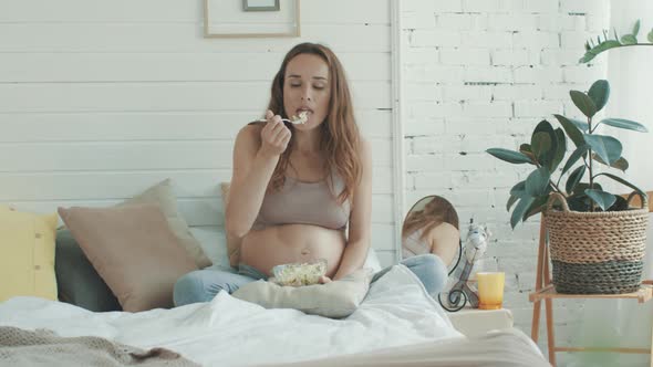 Pregnant Woman Eating Healthy Foods Bed. Expectant Mother Holding Bowl of Salad.